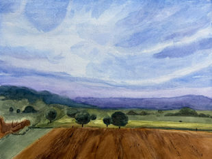 Watercolor landscape with a wide blue sky, distant purple hills, green fields, and a warm brown plowed foreground