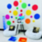 A bright, vibrant corner of a classroom with a bubble tube, dog beds, and other sensory elements