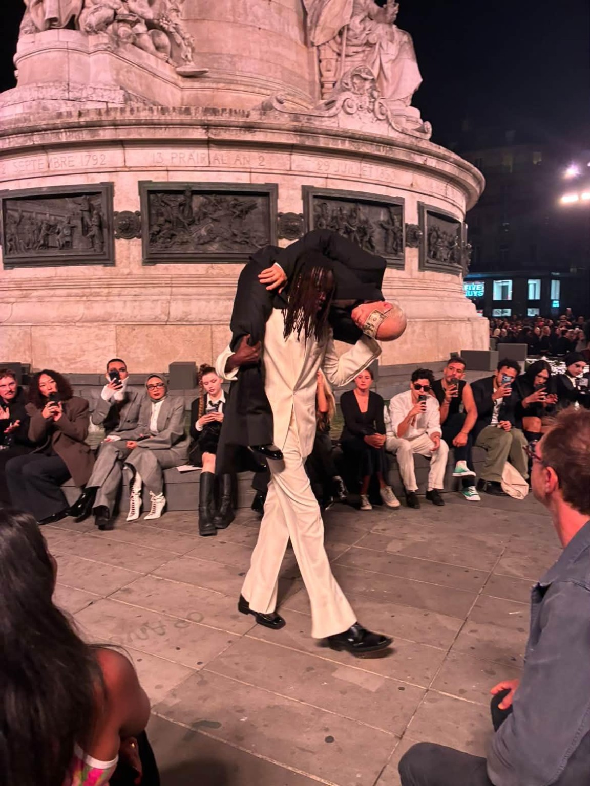Matières Fécales, The Ninety-Nine Percent. A performer in white carries a person dressed in black along the runway. Photograph: Jessy Collucci.