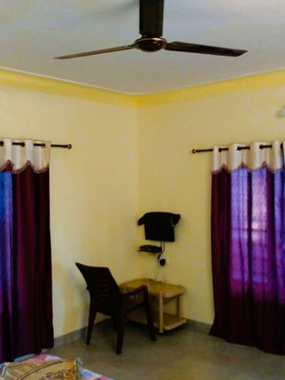 Room with purple curtains, desk, and fan