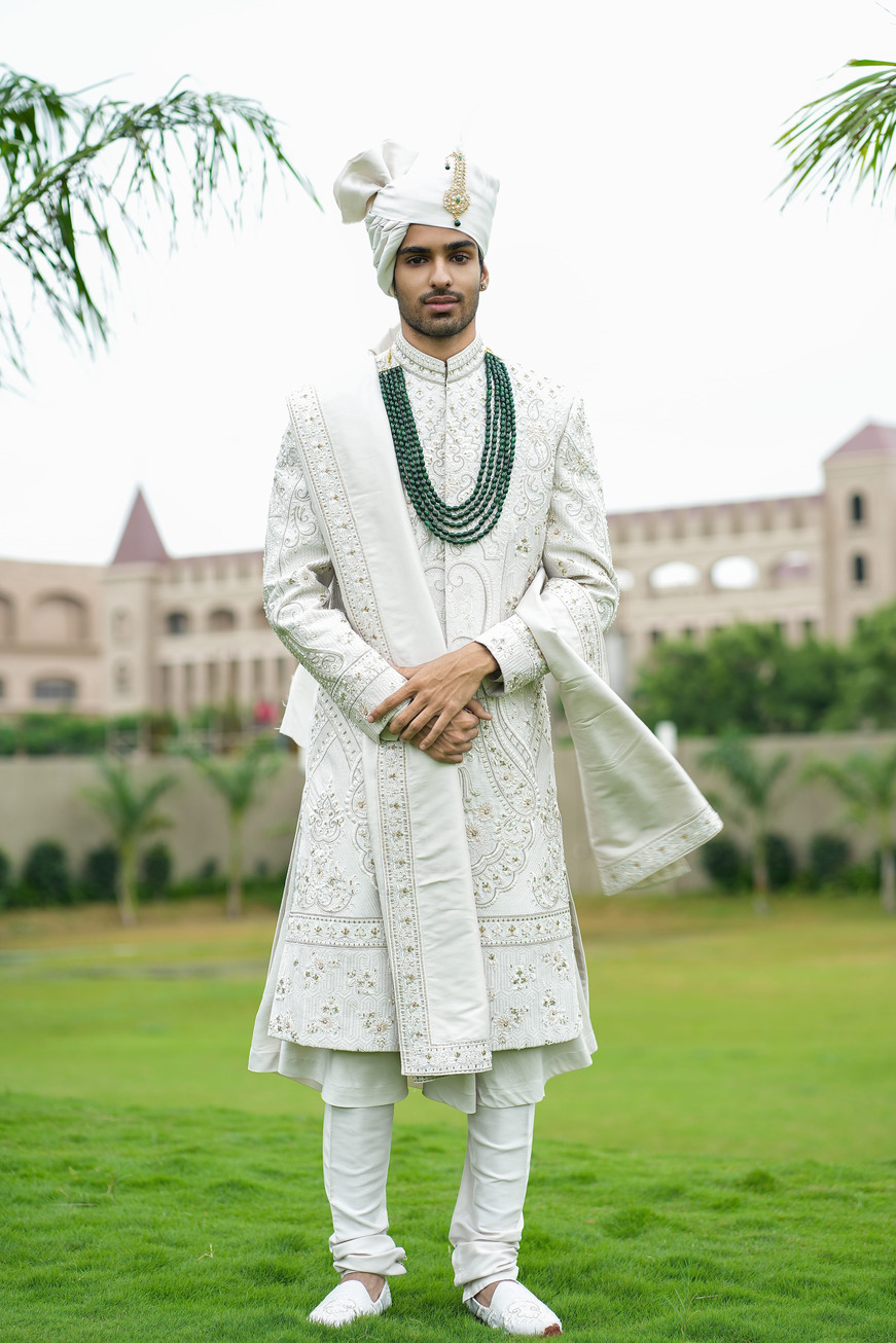Full length ivory sherwani for groom with anarkali kurta choodidaar and handwork dupatta – bespoke wedding wear by Clodor