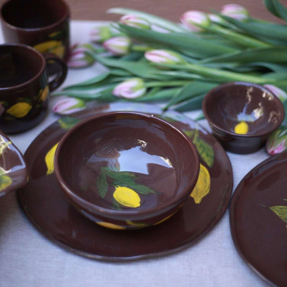 Ręcznie wykonany ceramiczny talerz z naturalnej gliny, w odcieniach brązu i żółtej cytryny, idealny do serwowania potraw.