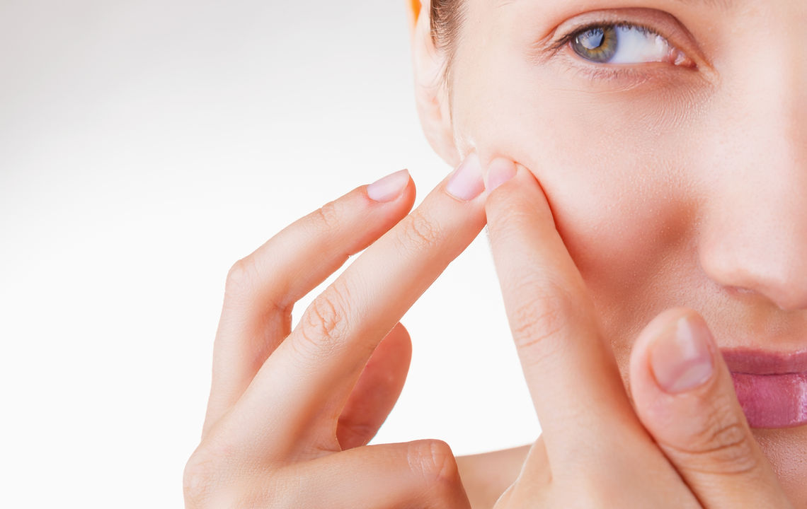 Woman is looking at her face after acne treatment in Vancouver.