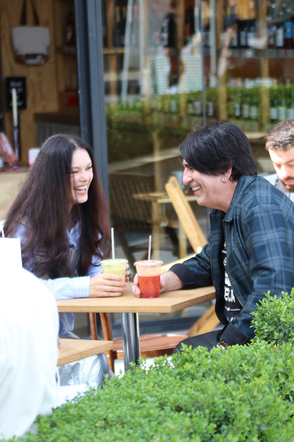 Martin and Natasha Blasick enjoying fresh juice at the Studio City Farmers Market, sitting at an outdoor table and smiling while engaged in conversation.
