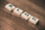 Scrabble tiles spelling "BLOG" on a wooden background, with each tile showing a letter and point value. Warm, rustic tones.