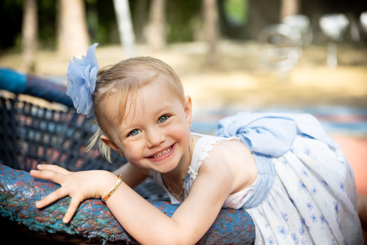 Little girl leaning on a play structure, smiling brightly.