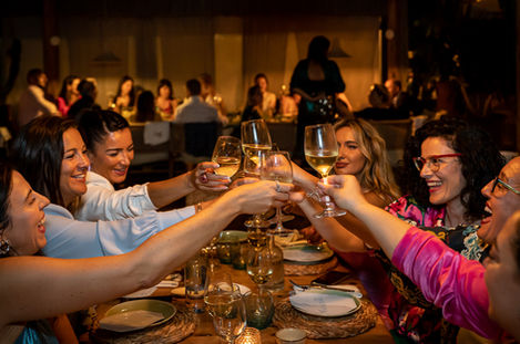 Friends raising glasses at a warmly lit dinner table.