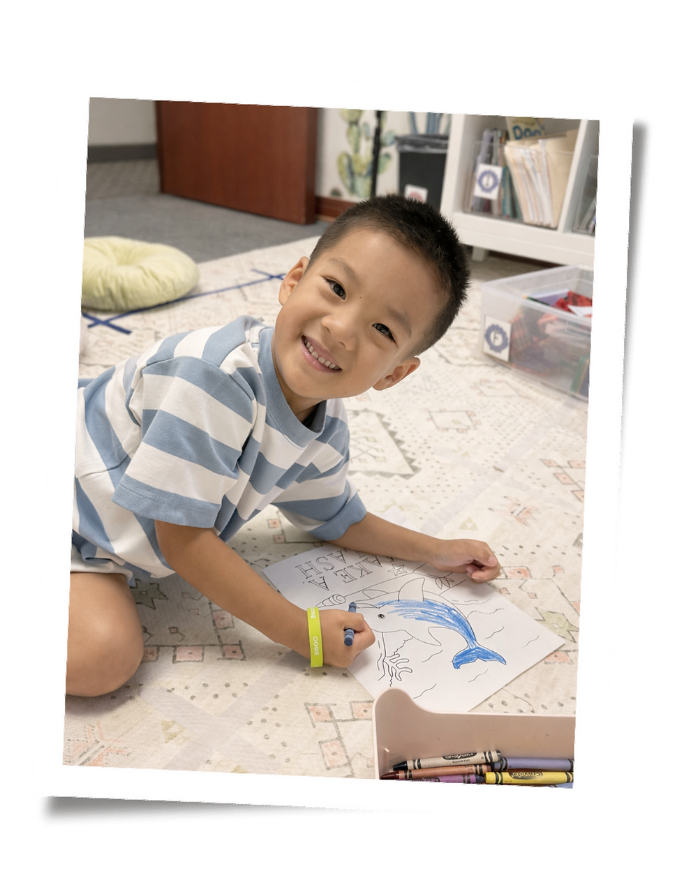 Young student smiling while coloring a worksheet