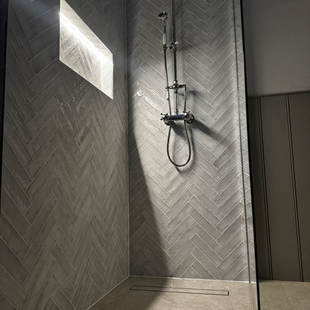 Walk-in shower installation in Baldock with herringbone tiled wall and rainfall system
