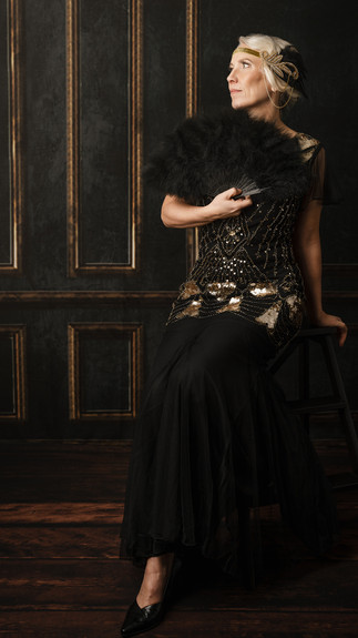 Nydelig dame som ser drømmende ut i luften. Hun har på seg klær i "Charleston" stil.