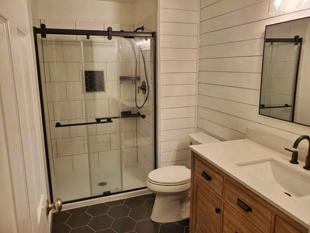 Custom master bathroom with walk-in tile shower, tile floors, updated lighting, and a new wood vanity.