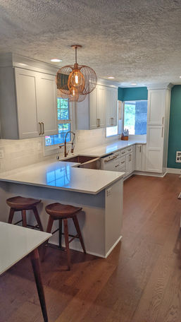Luxury kitchen remodel with wood flooring, custom cabinets, quartz countertops, tile backsplash, and new windows.