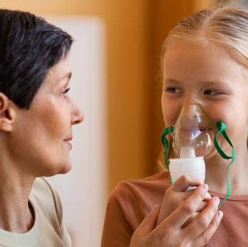 Mor giver datter maske på til maskebehandling for vejrtrækningsbesvær