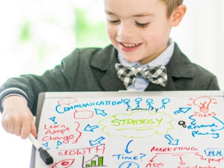 Child pointing at whiteboard with text on it