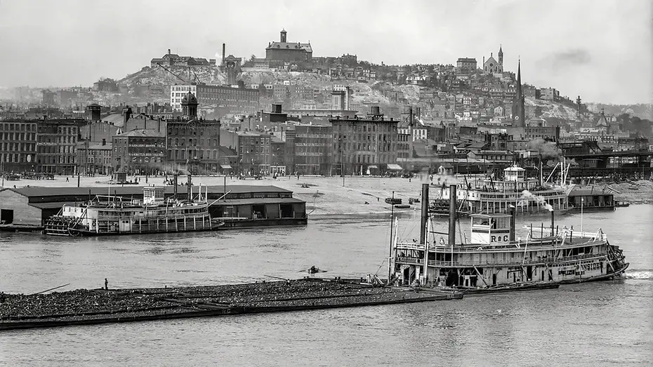 Historic black-and-white photograph of steamboats on the Ohio River with Cincinnati’s riverfront and hillside neighborhoods i