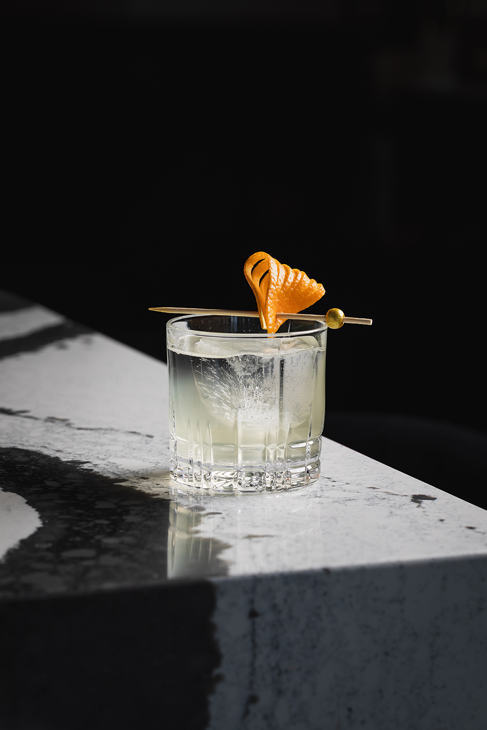 “Clear cocktail in a rocks glass with ice, close-up.”