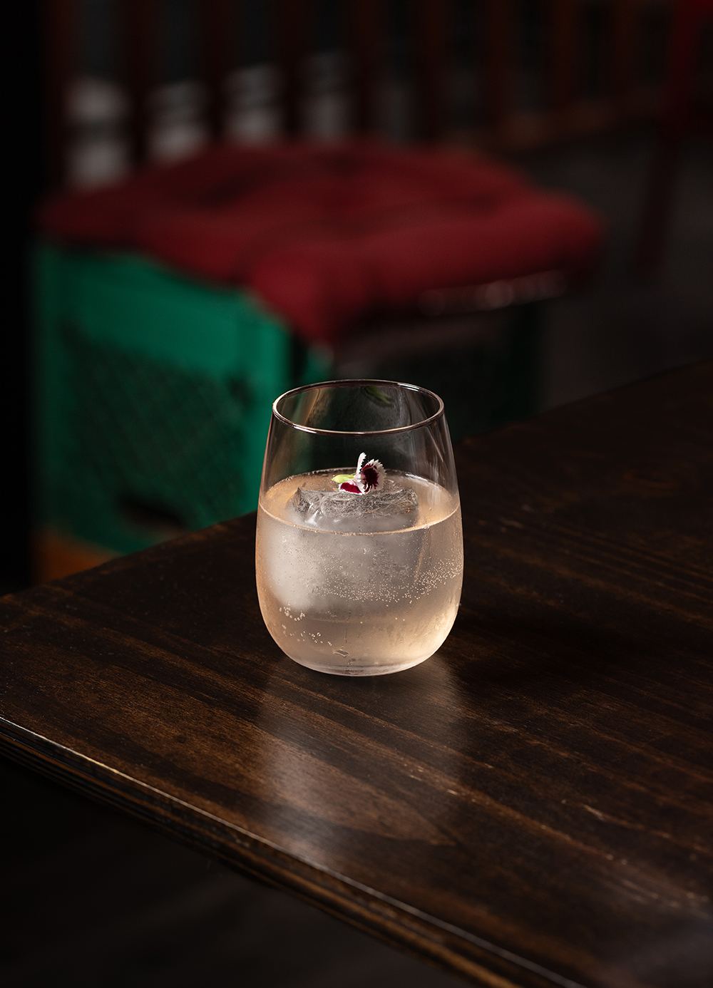 “Dark cocktail on a wooden bar top, low light.”