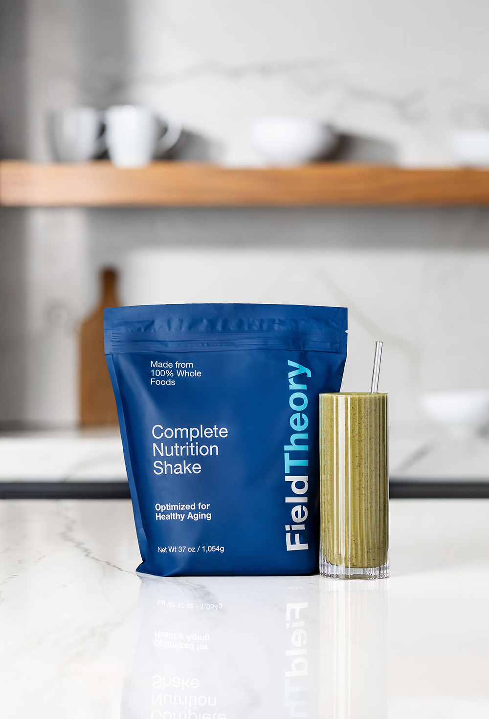 “Protein shake product package and tall glass on a kitchen counter.”