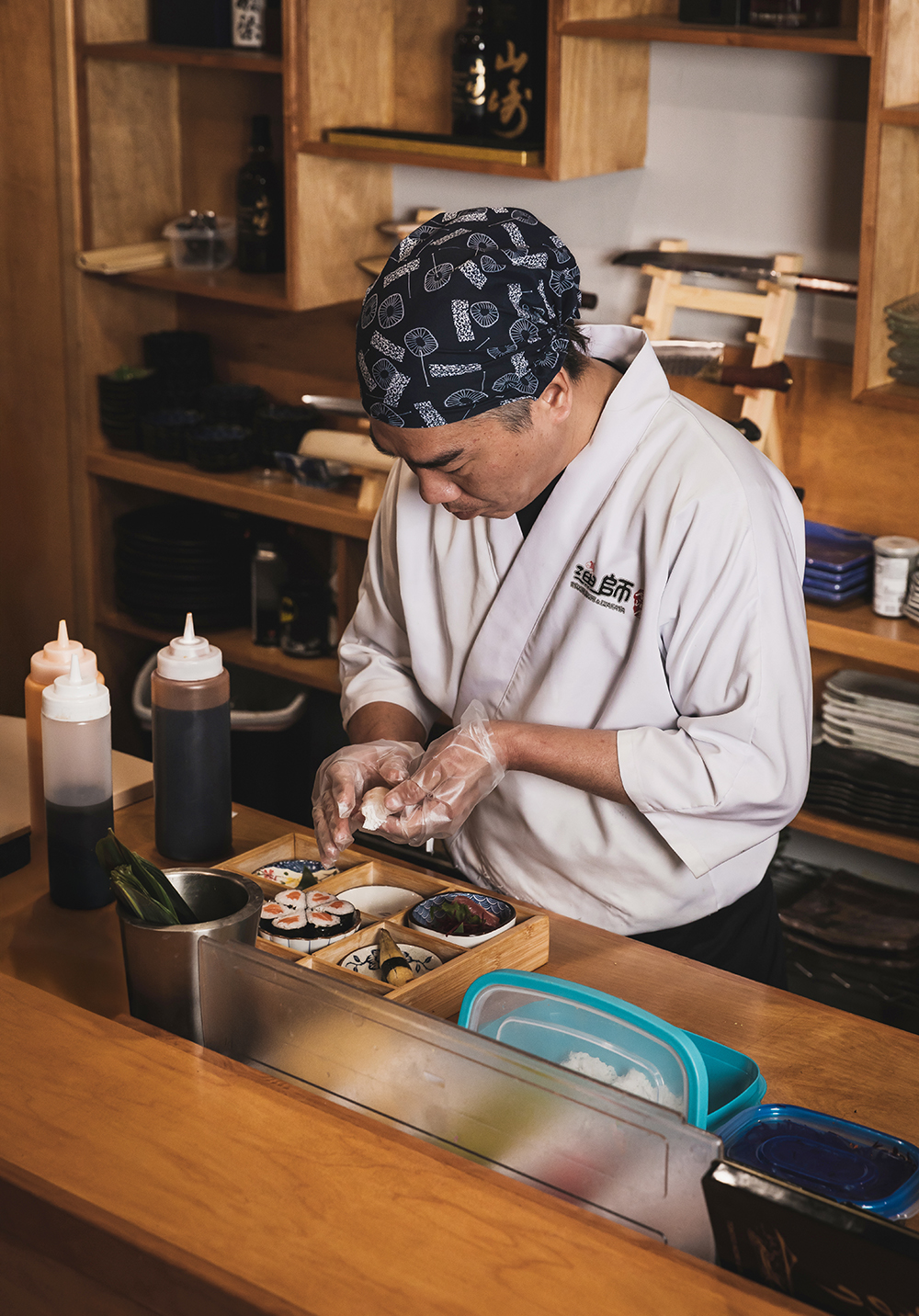 “Chef preparing food at a counter with squeeze bottles nearby.”