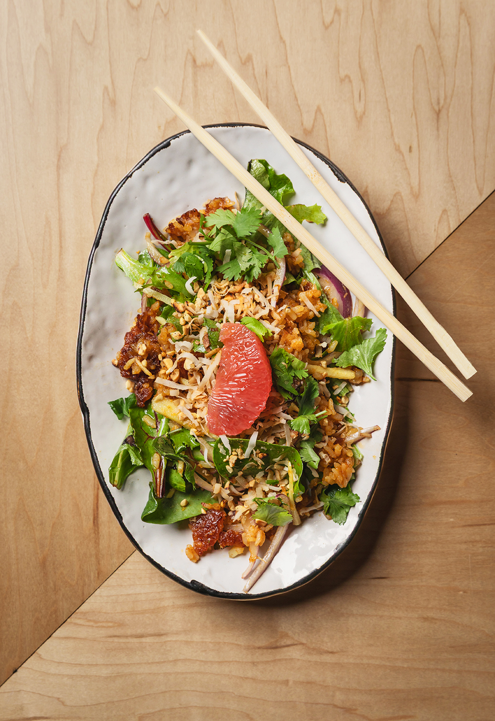 “Bowl of noodle salad with herbs and citrus, overhead food shot.”