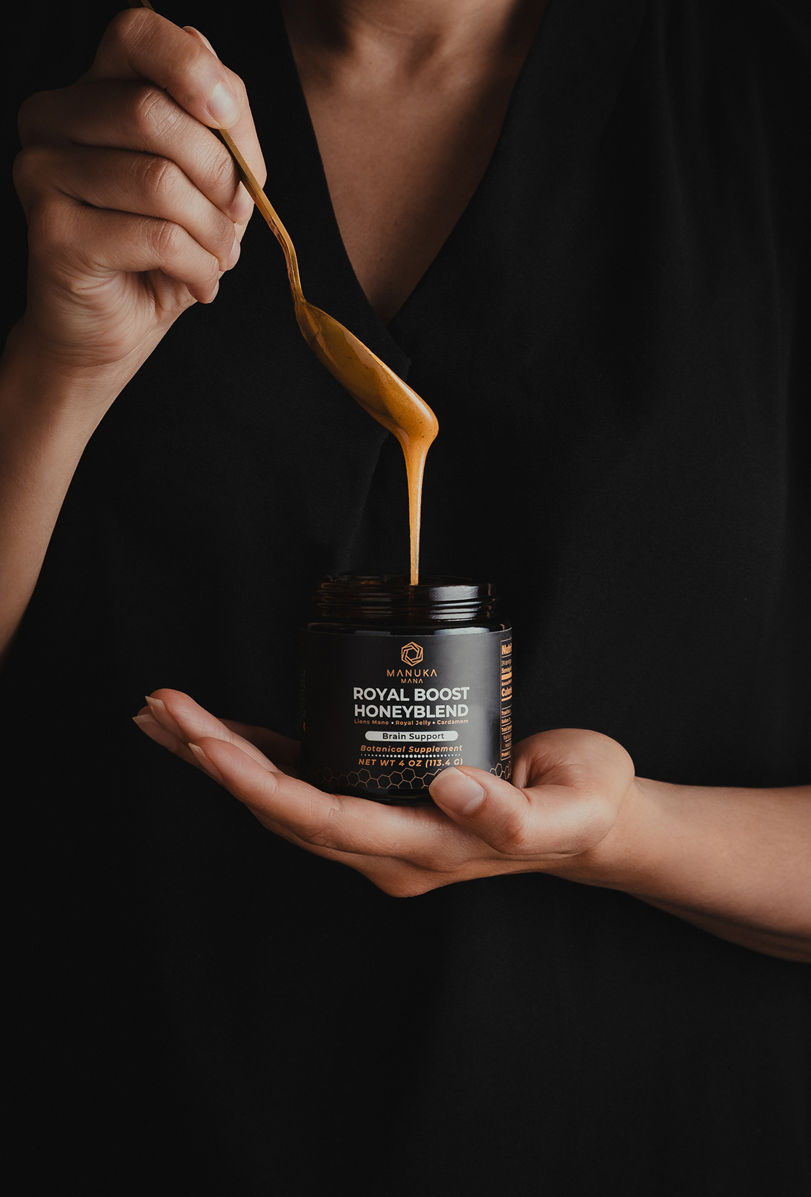 “Hands holding a small jar of honey with honey being drizzled from above.”