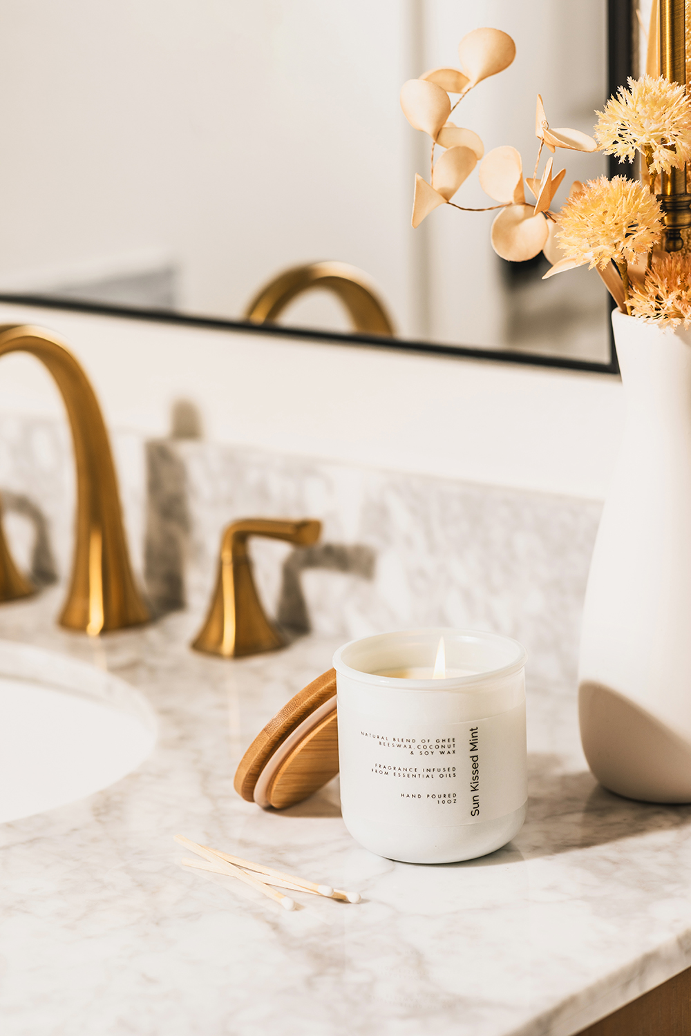 “Minimal product scene with candle jar near bathroom sink faucets.”