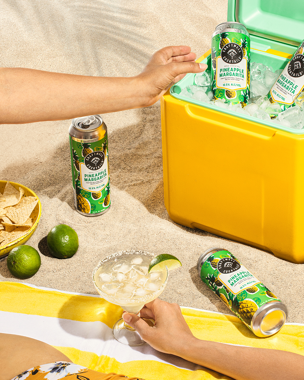 “Canned cocktail drink styled with citrus and a yellow cooler in the background.”