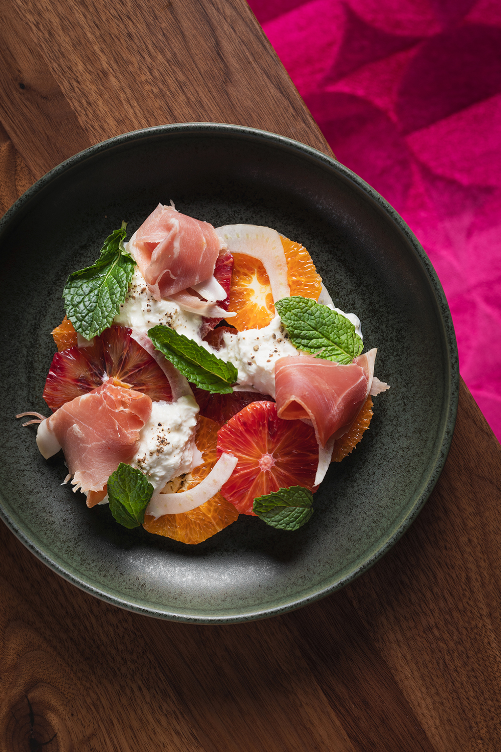 “Plated dish topped with cured meat and herbs, overhead.”
