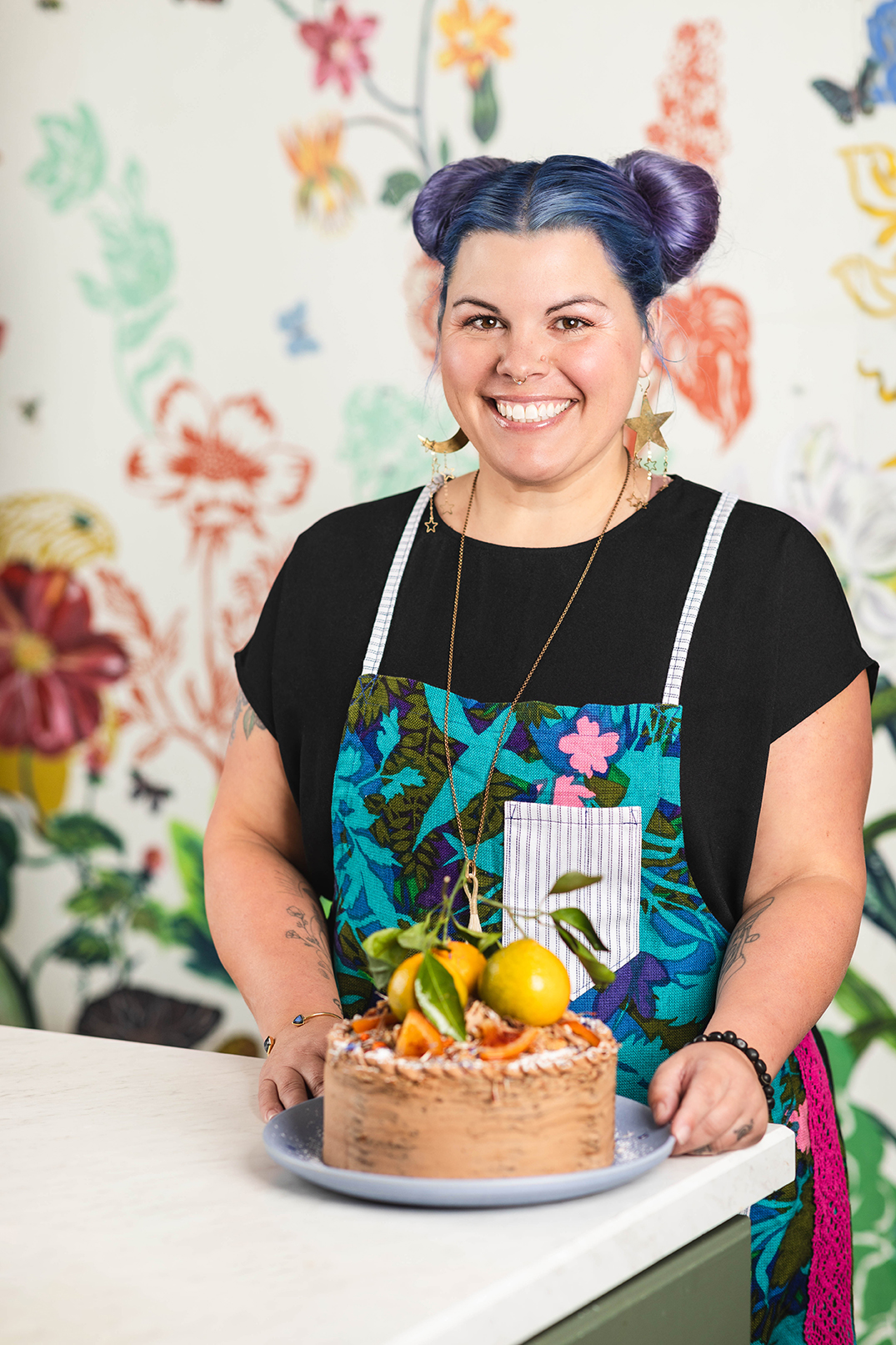 “Smiling chef in apron holding a plate of citrus fruit, portrait.”