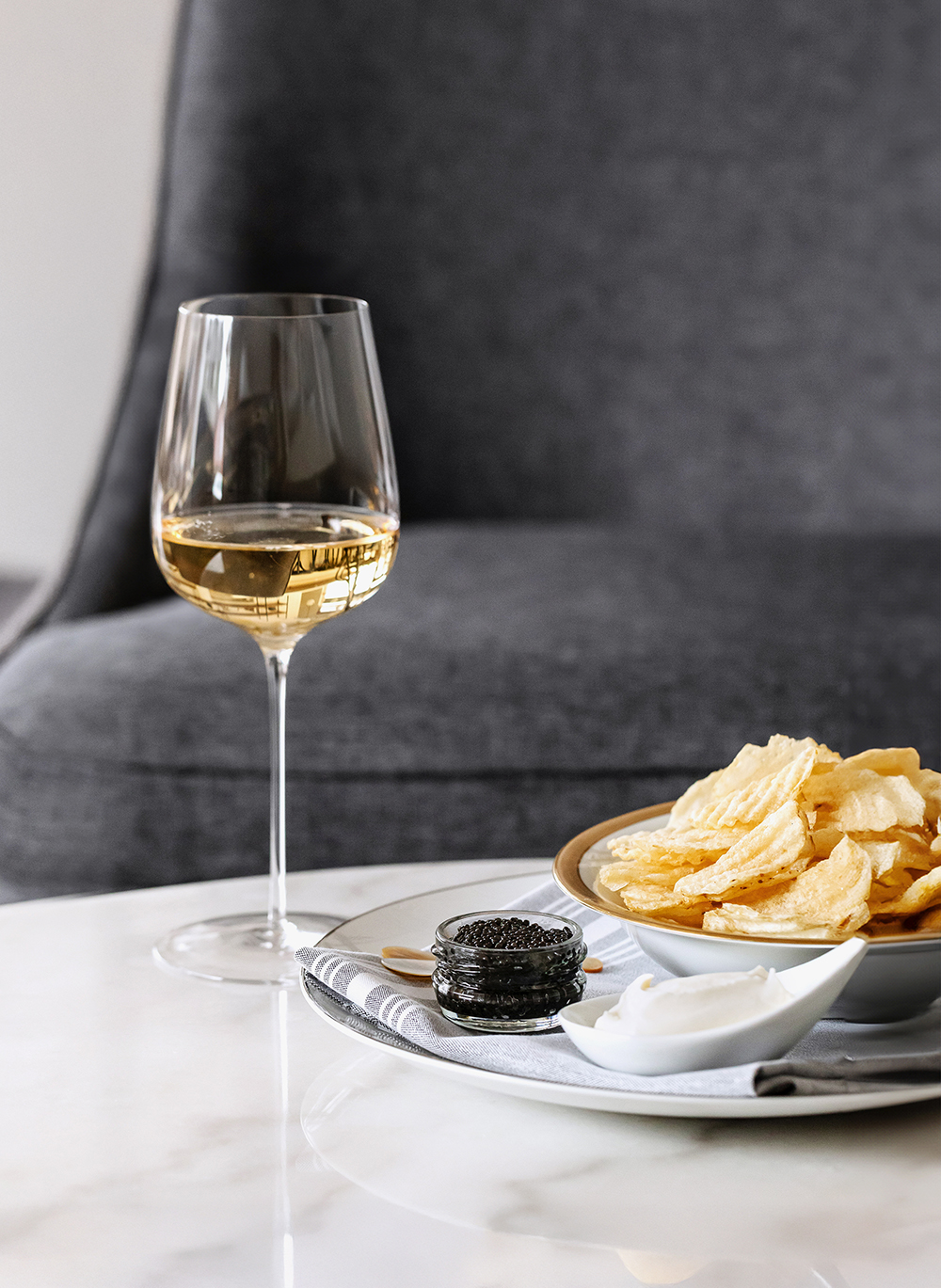 “White wine glass beside plated food, table setting.”
