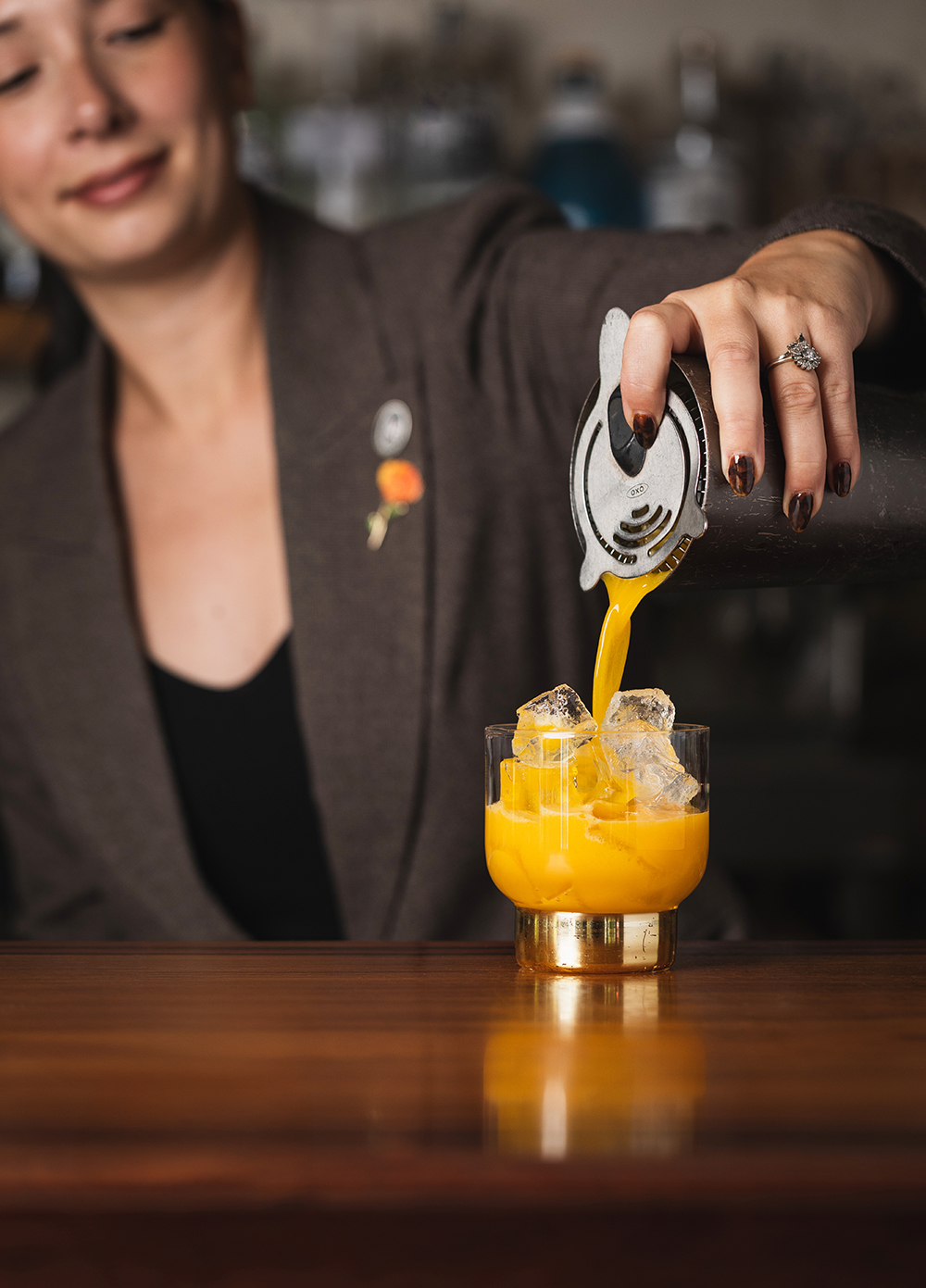 “Hand holding a citrus peel over a cocktail, garnish moment.”