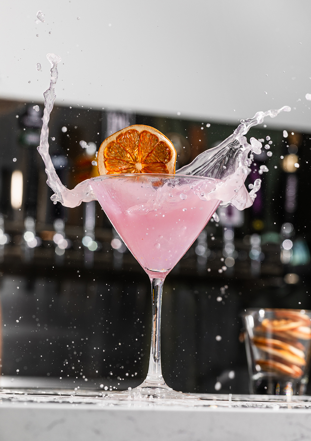 “Pink cocktail splash in a coupe glass, action drink shot.”