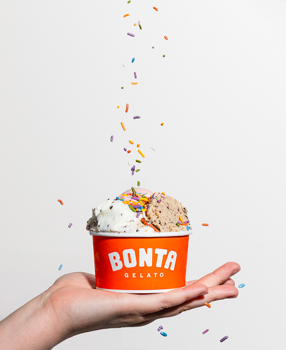 “Hand holding an ice cream cup topped with colorful sprinkles.”