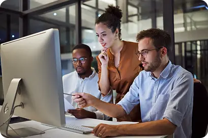 Grocery pricing optimization team analyzing data on a desktop computer for retail margin management and AI-powered price planning.