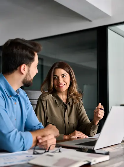 Business professionals collaborating at a laptop in a modern office, representing workflow coordination and enterprise execution.