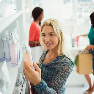 Woman examining a perfume bottle while shopping in a beauty store.