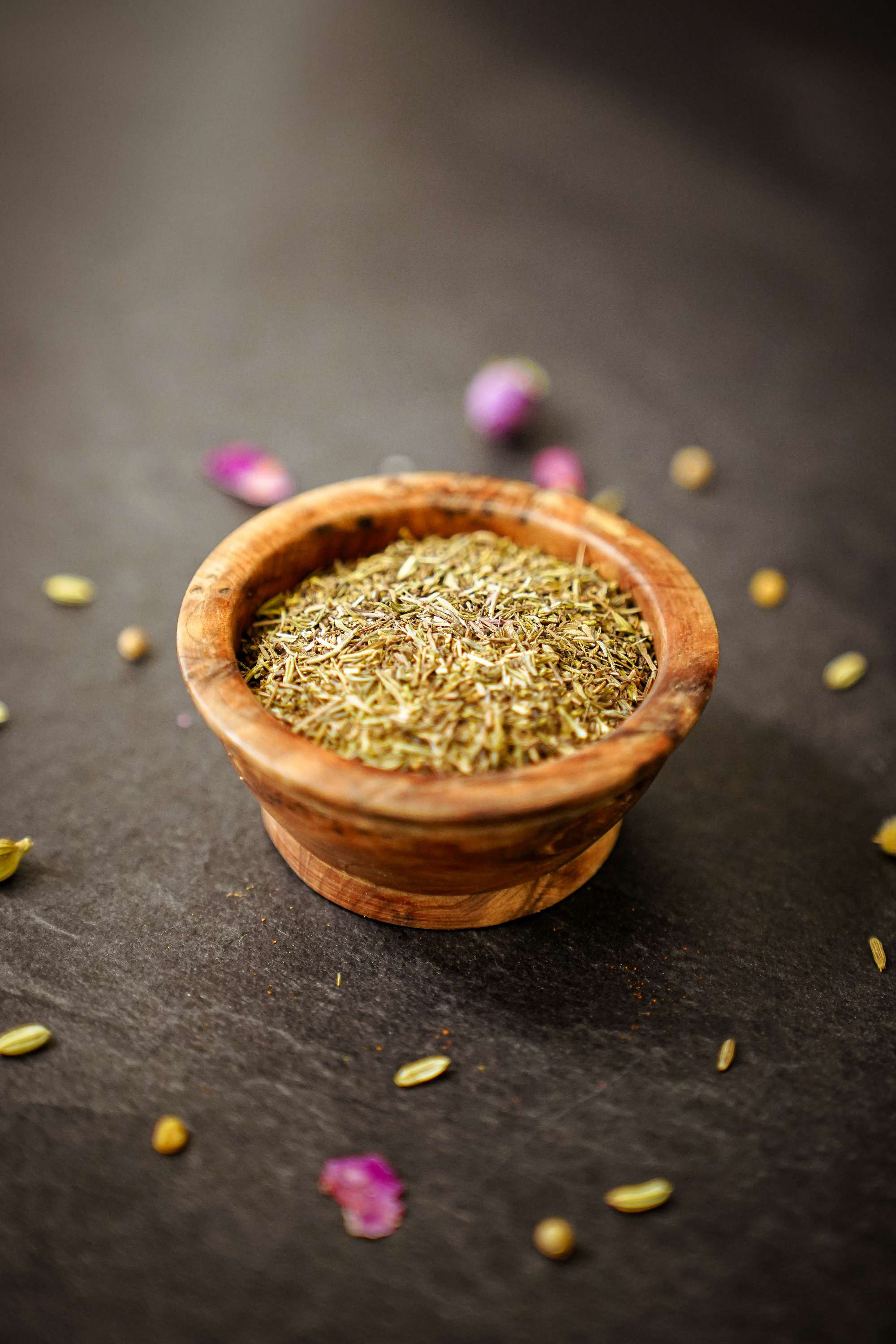 Brins de thym bio frais et séchés, présentés dans un petit bol en terre cuite avec des feuilles en arrière-plan