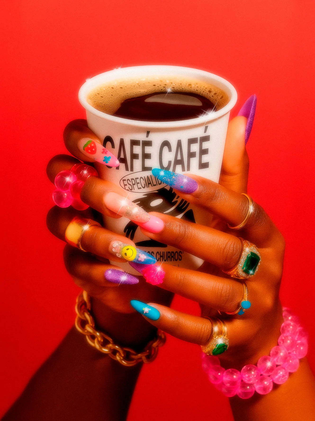 Churros Churros café branding shown through a close-up of a branded coffee cup held by hands with colorful nails against a red background.