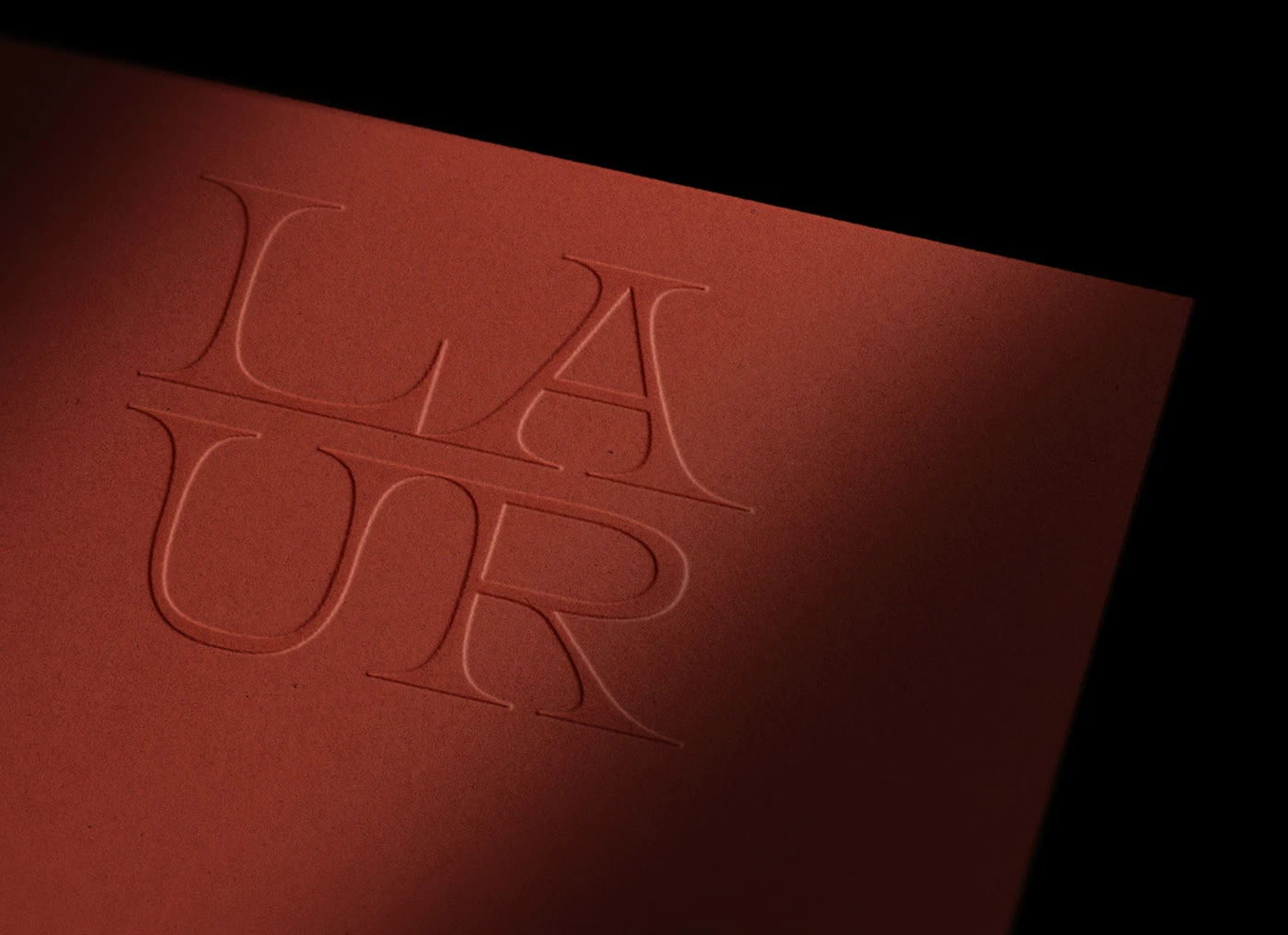 Close-up of Laur logo debossed on terracotta paper, highlighting modern minimalist branding, refined typography, and contemporary tactile design direction for interior design studios.