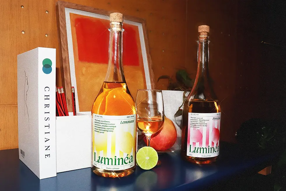 Two Luminéa wine bottles displayed on a shelf with a glass of wine, lime slice, and art prints in the background, emphasizing the brand’s premium packaging design and lifestyle presentation.