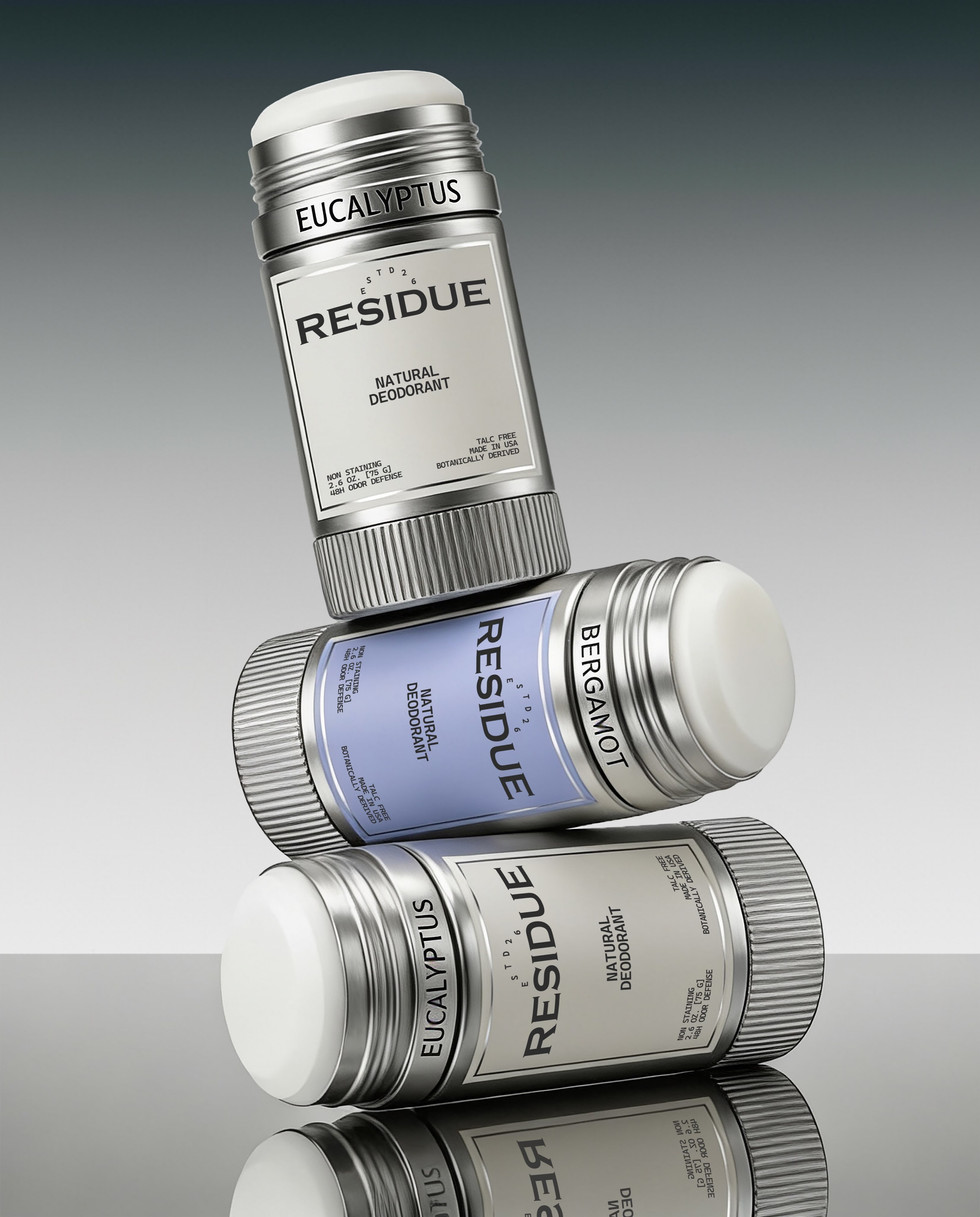 Three natural deodorant sticks stacked diagonally, showcasing silver packaging, white and powder blue labels, exposed deodorant formula, and engraved fragrance names.