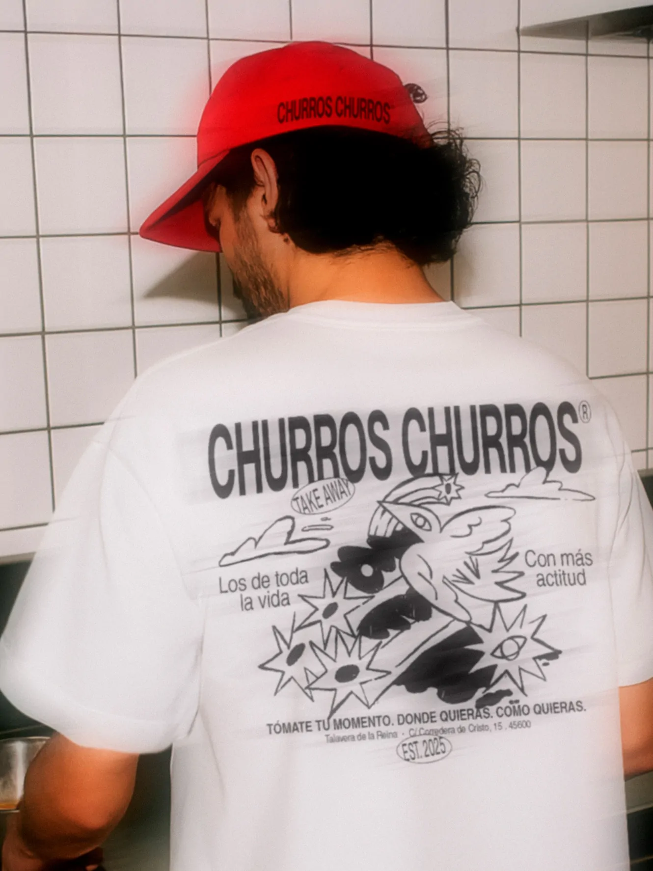 Churros Churros merchandise design featuring a staff member wearing a branded t-shirt and cap with illustrated graphics on the back.