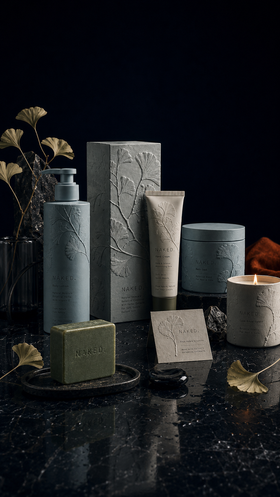 NAKED. skincare product lineup with body lotion, hand cream, bath soak, mineral soap, candle, and embossed botanical packaging on a dark reflective surface.