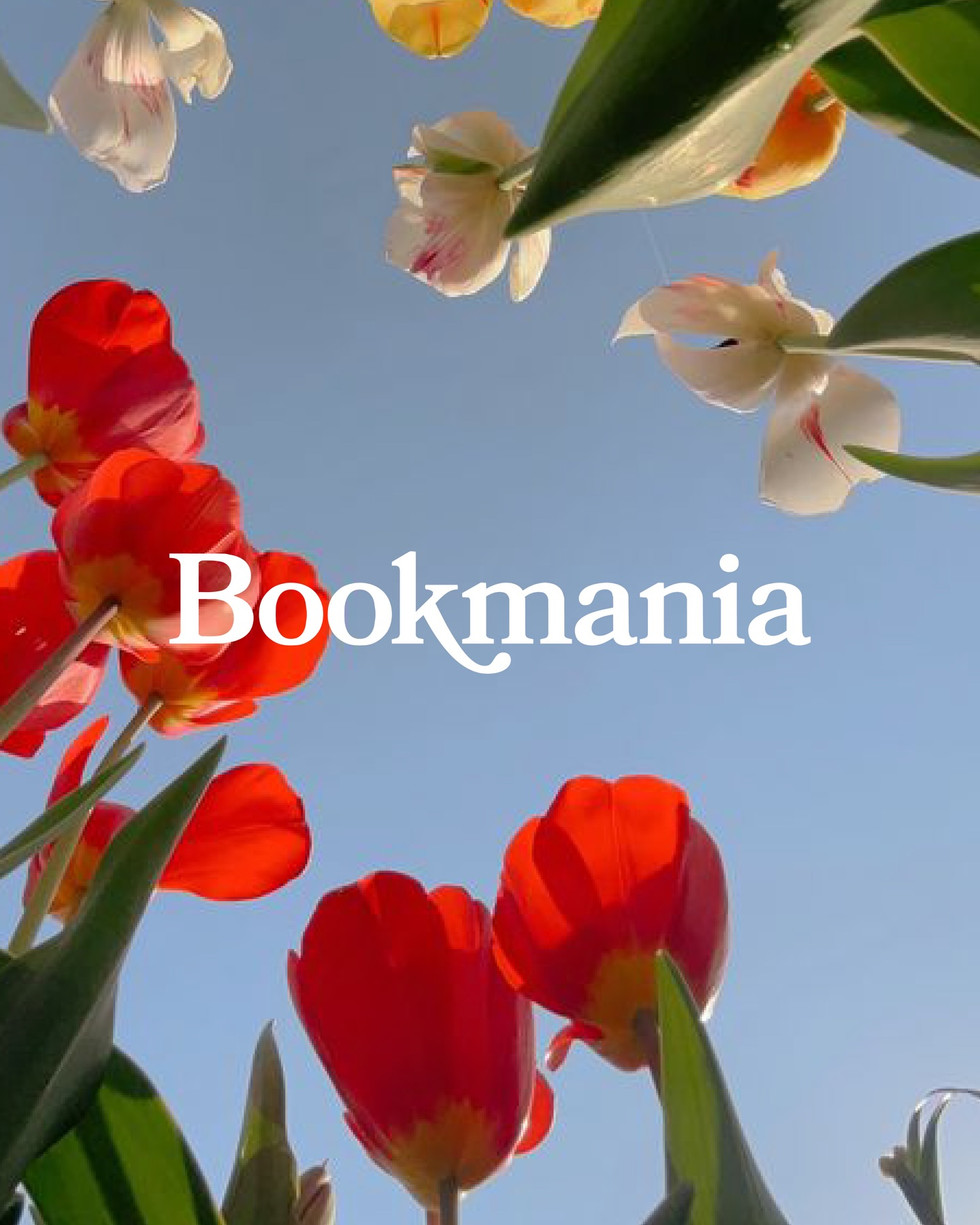 White serif font sample reading “Bookmania” placed over red tulips, white flowers, green leaves, and a pale blue sky background.