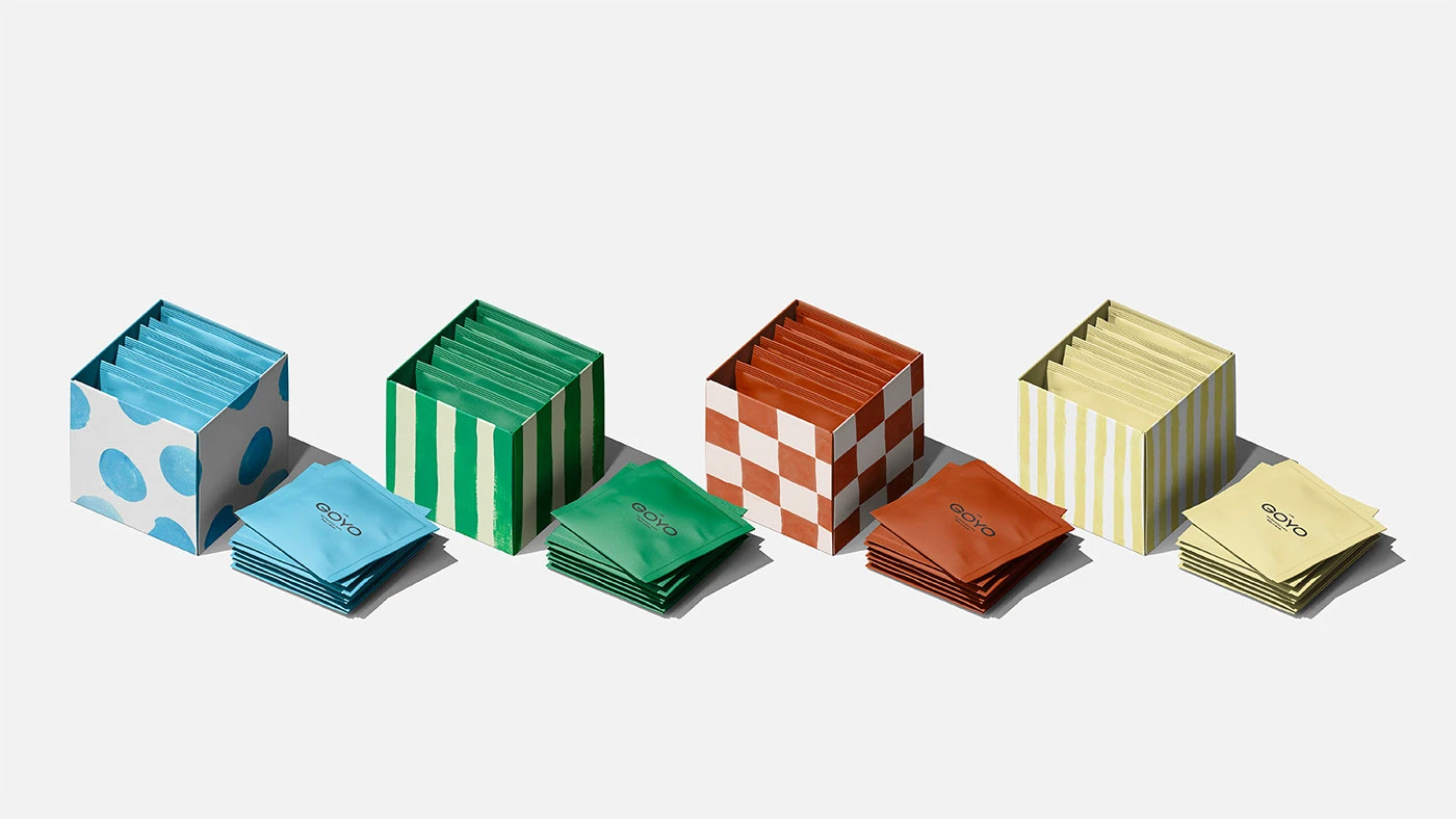 Open Goyo Tea packaging boxes in blue, green, terracotta, and yellow with matching patterned interiors, showing organized tea sachets in minimalist editorial style