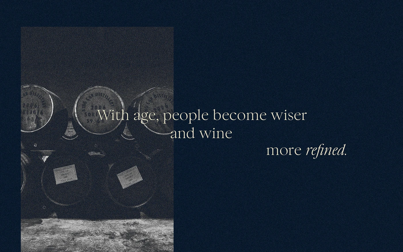 A moody, grainy black and white photograph of wine barrels in a cellar, featuring a centered brand quote about age and refinement in elegant white serif typography.