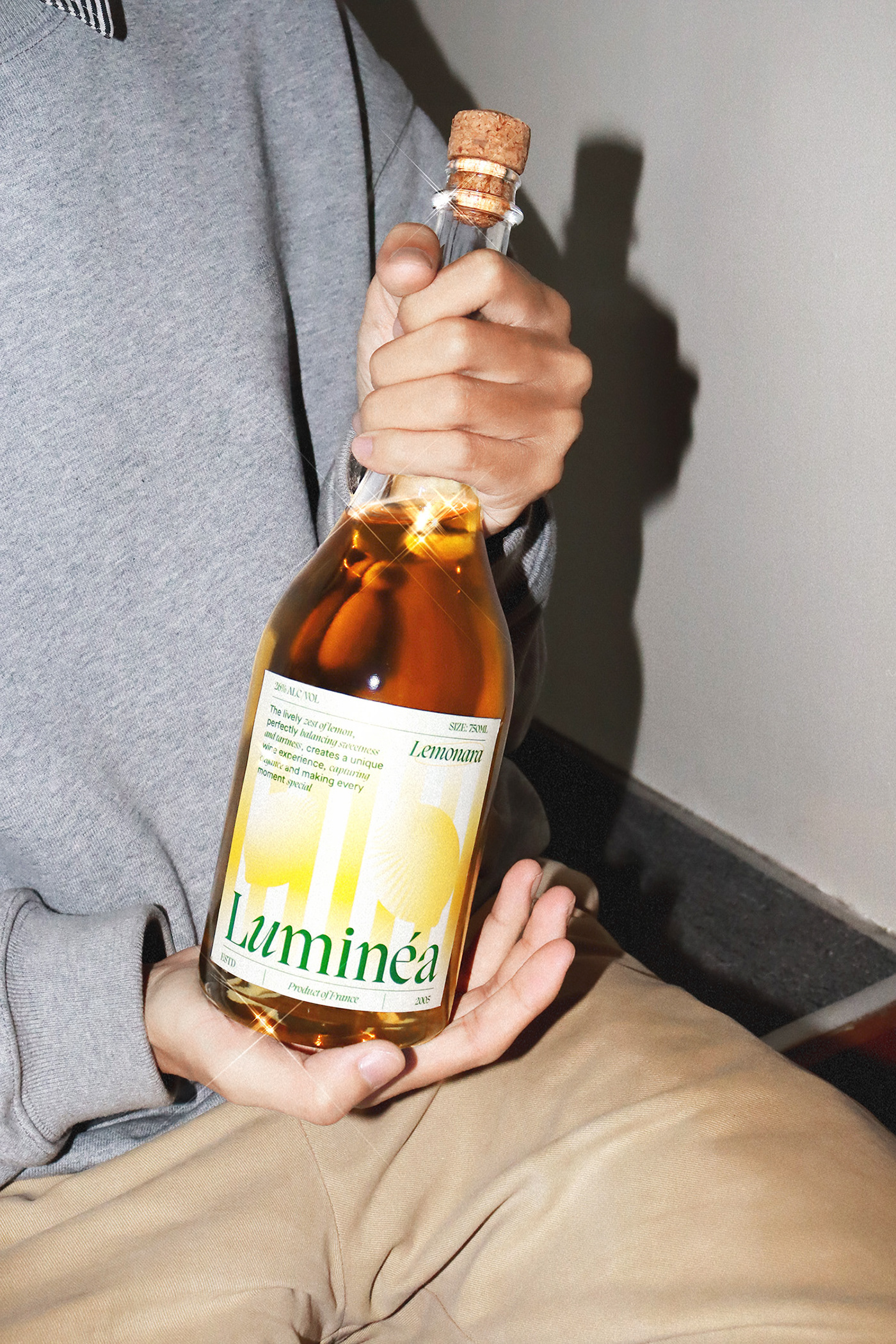 Close-up of a hand holding a Luminéa Wine bottle, showing the gradient yellow label with editorial typography and premium packaging details.