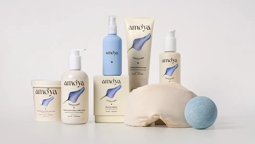 Amo’ya Odpoczynek self-care collection featuring blue and cream body-care packaging, a candle, wellness tub, eye pillow and blue bath bomb arranged on a pale studio background.