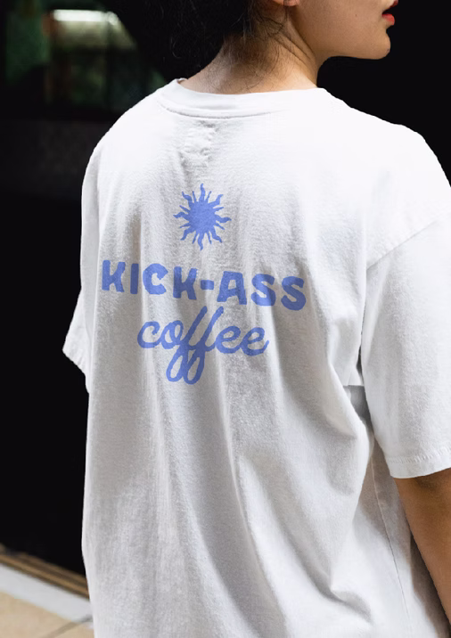 Cowgirl Coffee Co. apparel design—back of a white T-shirt with “Kick-Ass coffee” in heritage blue, showcasing brand typography and merch direction by Yana Studios.