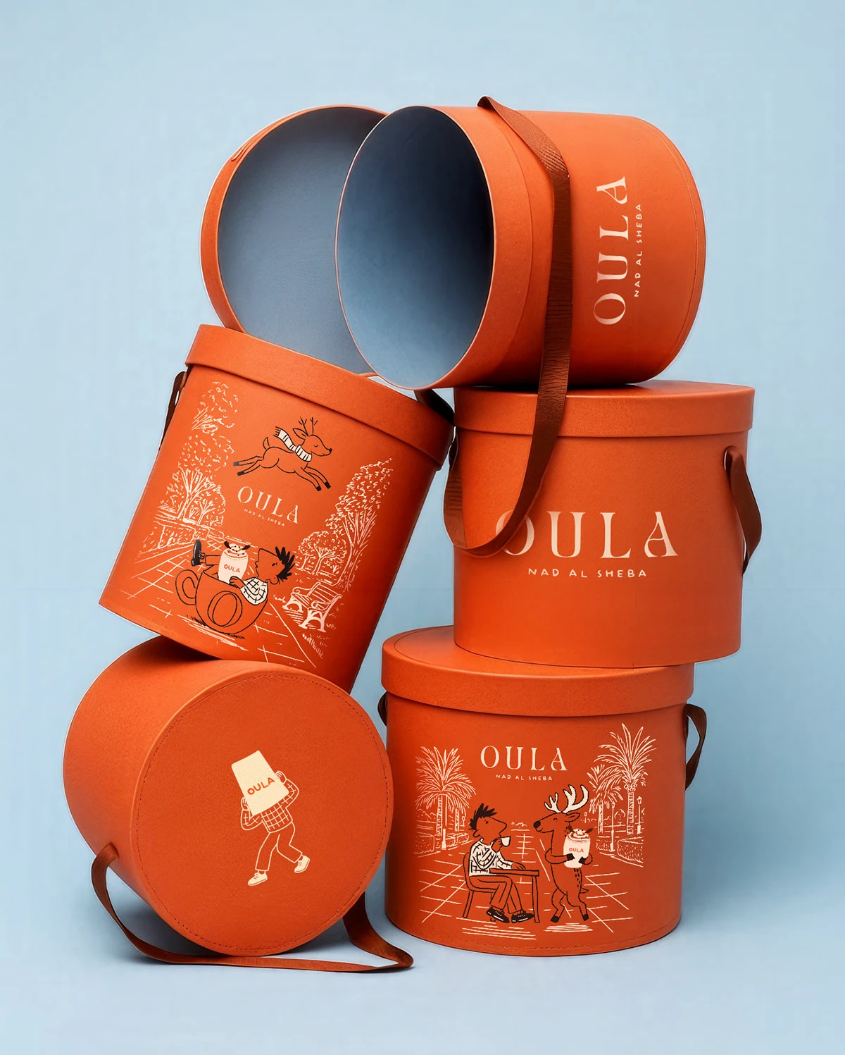 Stacked OULA round packaging boxes featuring illustrated characters and reindeer graphics for the Dubai seasonal coffee pop-up brand identity.
